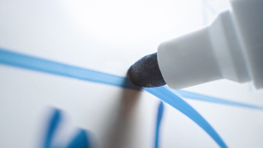 Close up of whiteboard marker writing on whiteboard.